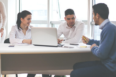 Three people sitting at a table with laptops